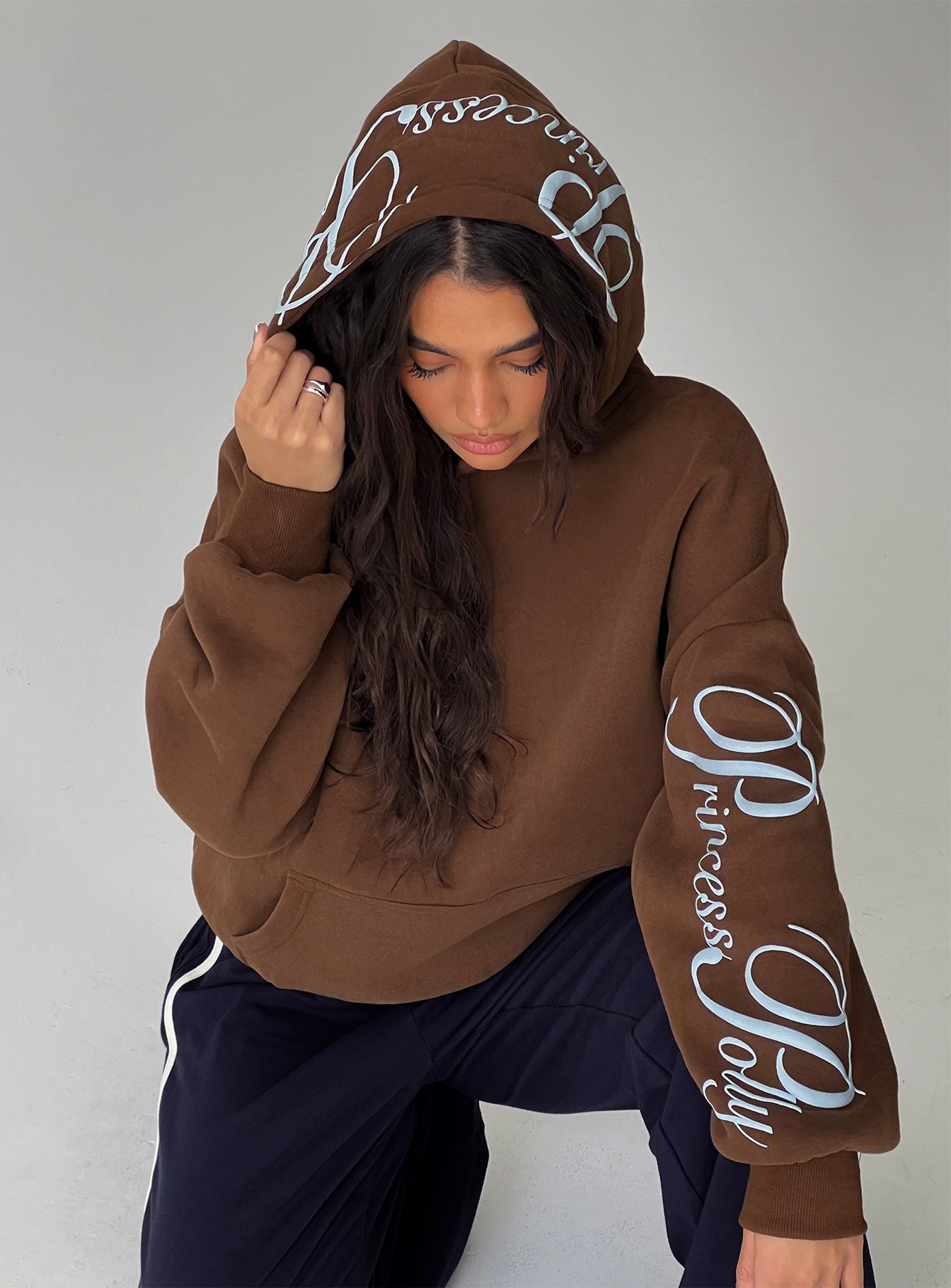 side view of model wearing Princess Polly Princess Polly Script Text Graphic Hoodie Brown / Blue Long 