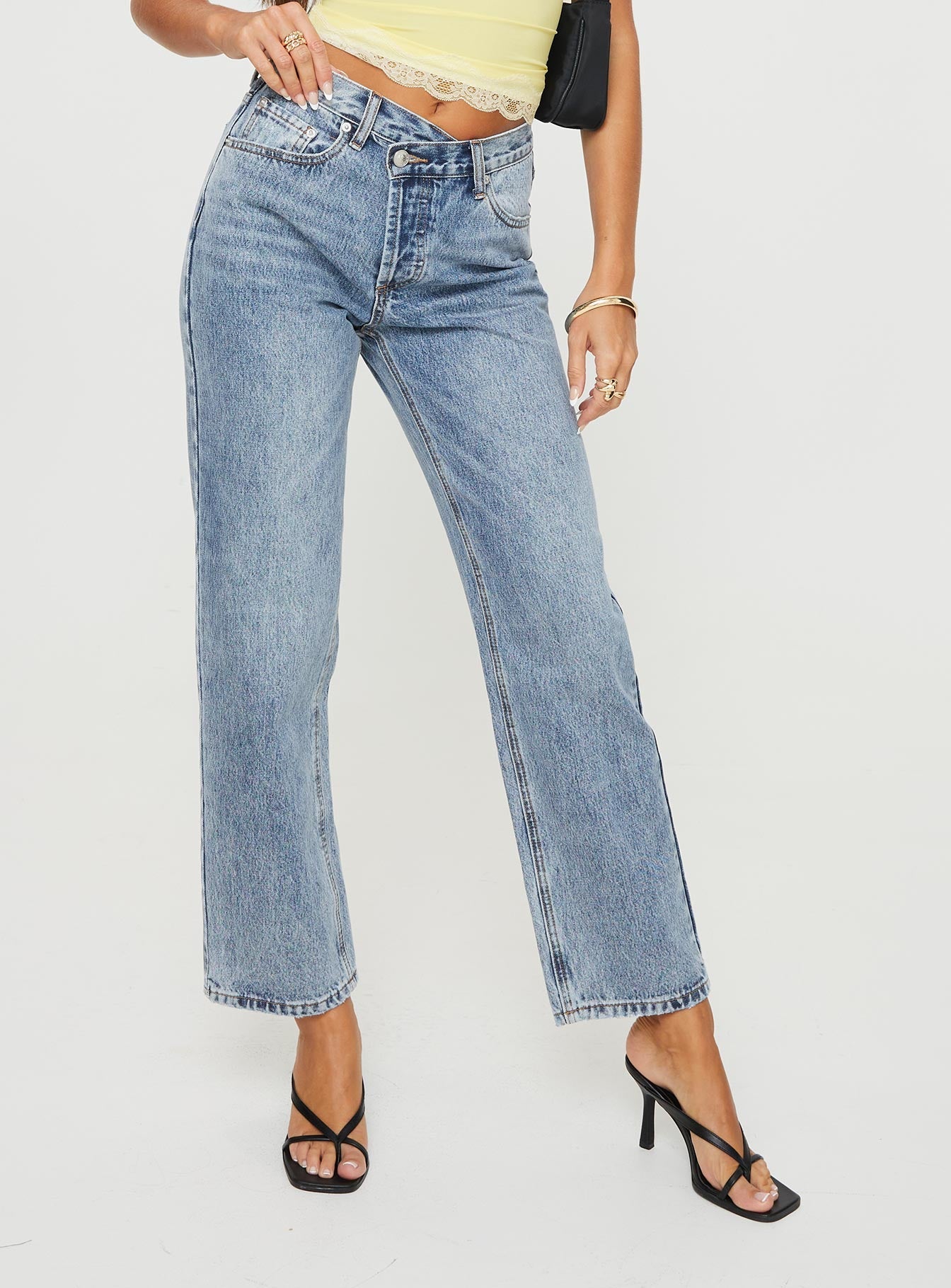 Mid rise denim jeans Asymmetrical waistband, relaxed straight leg, button front fastening, belt loops at waist, distressed detailing on hem