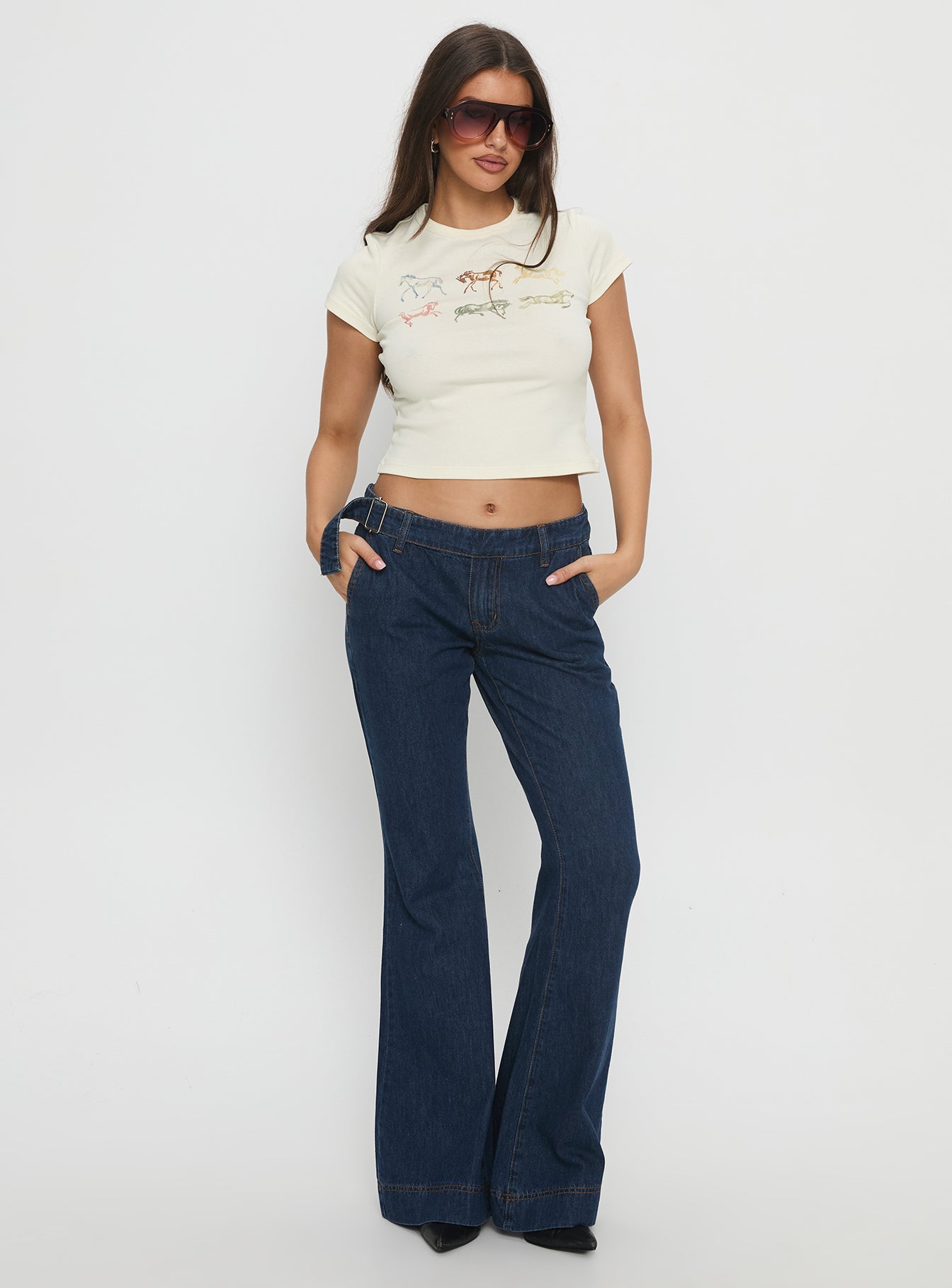 side view of model wearing Princess Polly Acapulco Low Rise Flare Jeans Dark Blue Wash Low Rise Jeans 