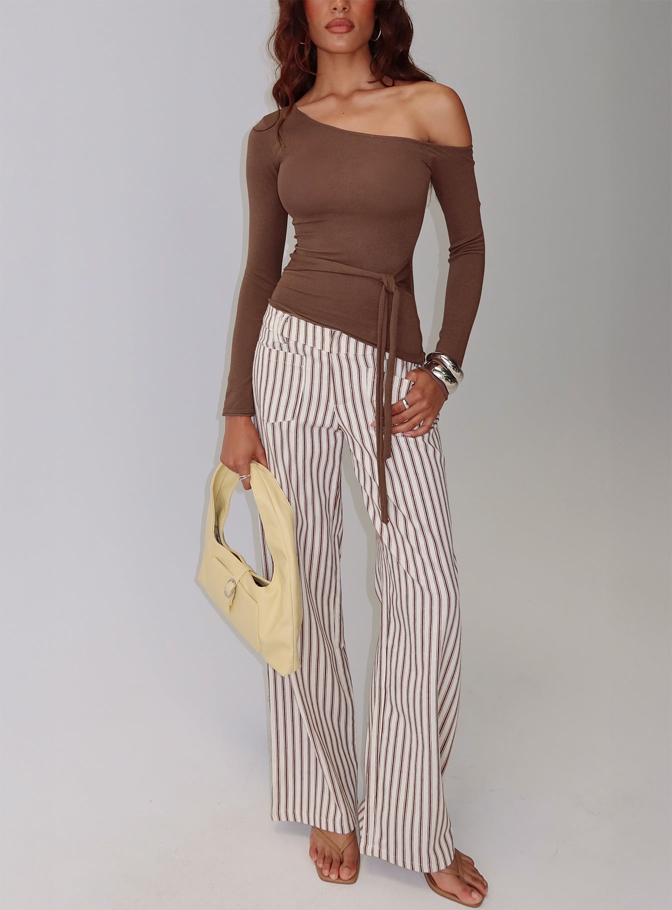 side view of model wearing Princess Polly Vendi Low Rise Pant Brown Stripe Low Rise Pants 