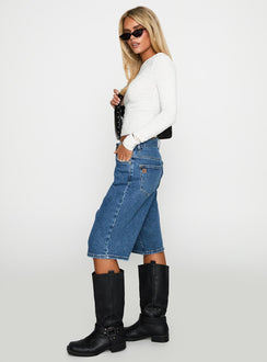 side view of model wearing Princess Polly Retro Dream Mid Rise Longline Denim Shorts Mid Wash Low Rise Shorts 