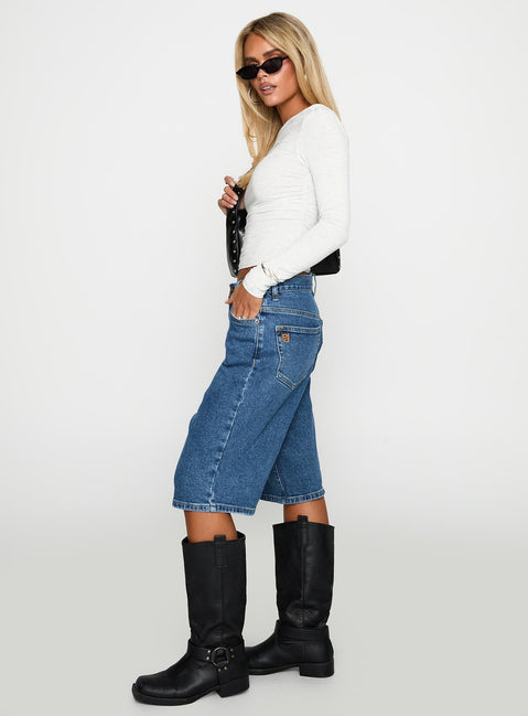 side view of model wearing Princess Polly Retro Dream Mid Rise Longline Denim Shorts Mid Wash Low Rise Shorts 