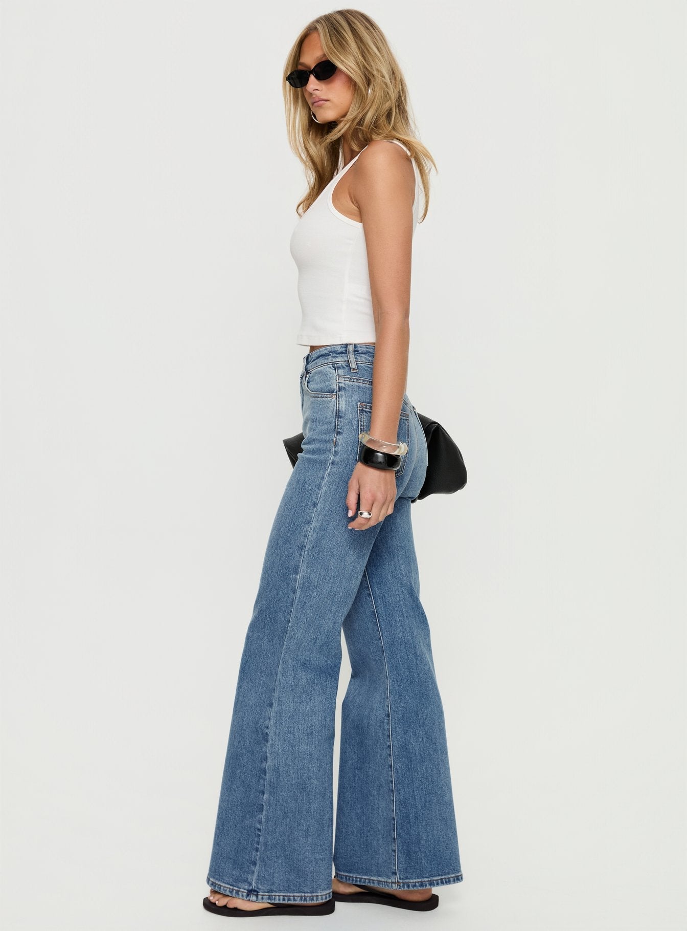 side view of model wearing Princess Polly Thearlie High Rise Flared Jeans Mid Blue Wash High Rise Jeans 
