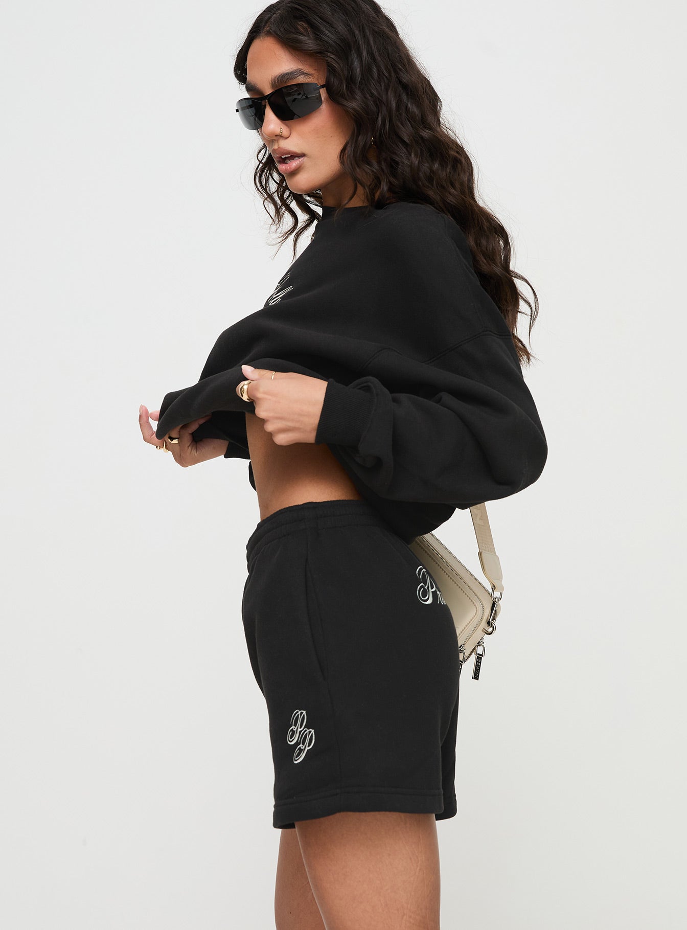 side view of model wearing Princess Polly Princess Polly Track Shorts Cursive Text Black Sand High Waisted Shorts 