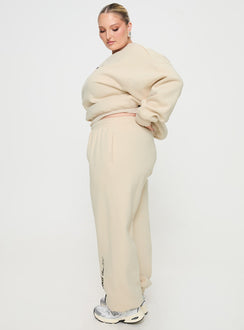 side view of model wearing Princess Polly Princess Polly Track Pants Block / Cursive Text Stone Curve High Waisted Pants 