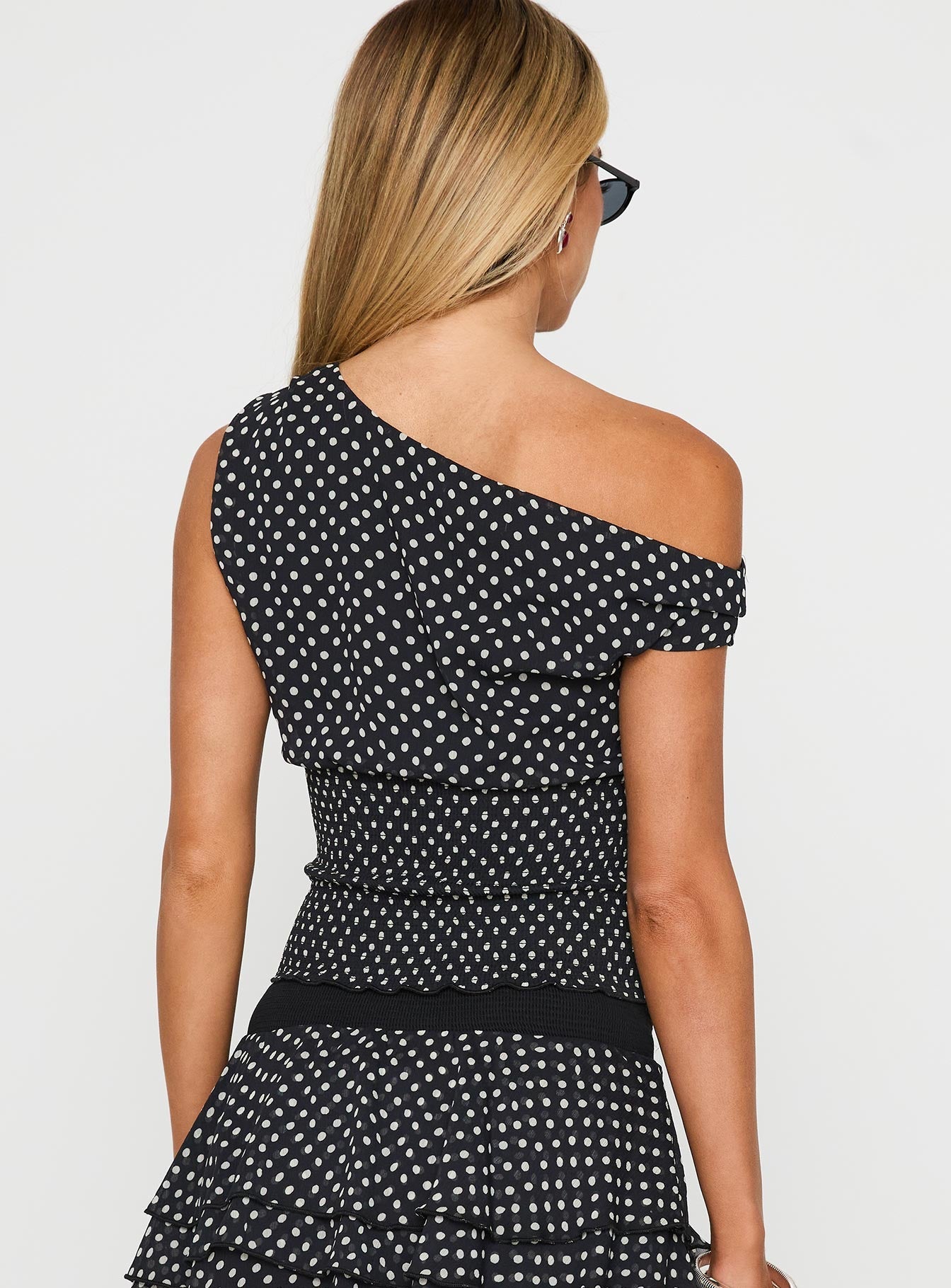 back view of model wearing Princess Polly Ready To Party Off Shoulder Top Black Polka Sleeveless Asymmetric Neckline 