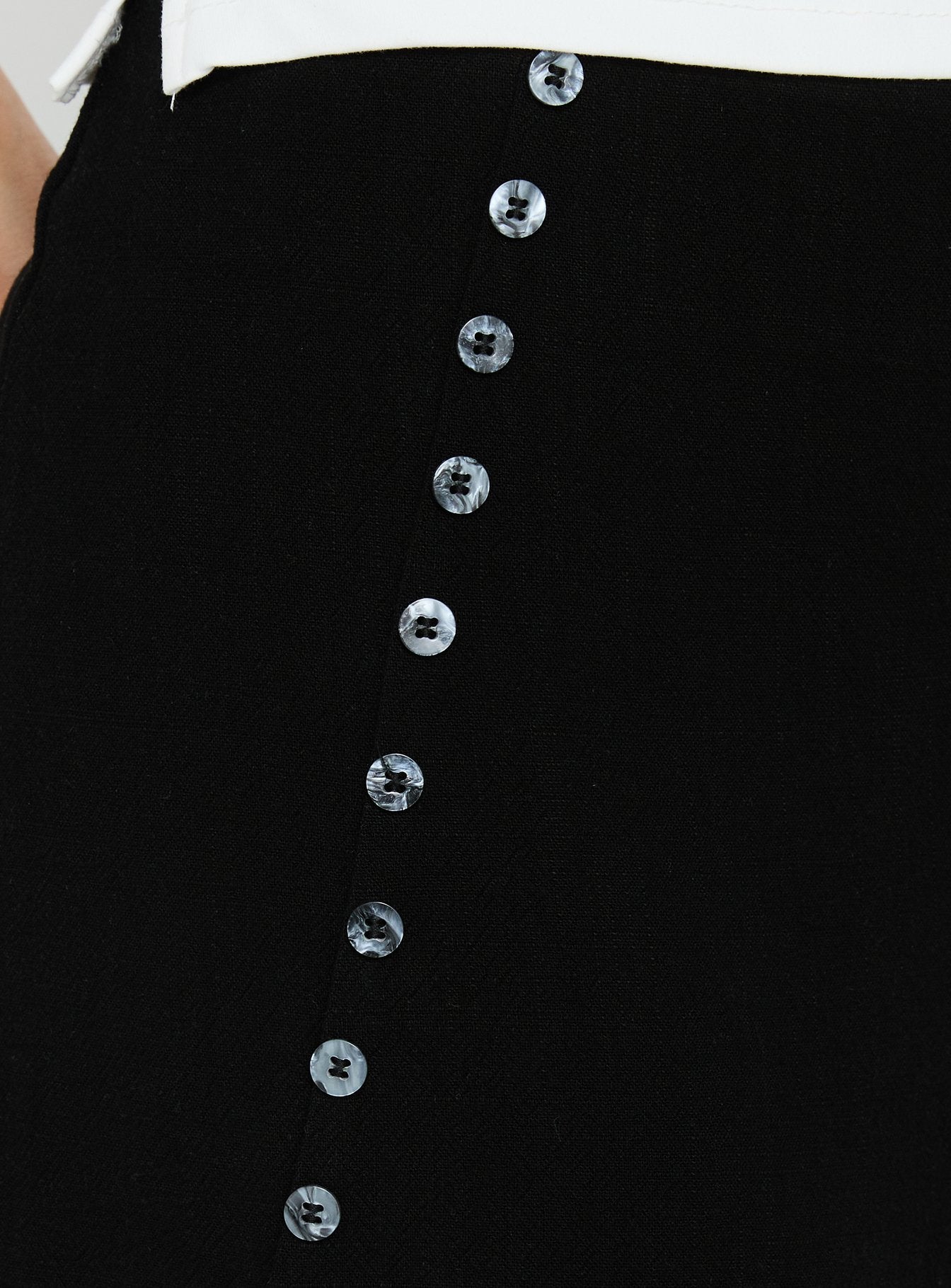 Highlighting the Leonelle Asymmetrical Button Mini Skirt Black womens-skirts in mini length detail view Princess Polly