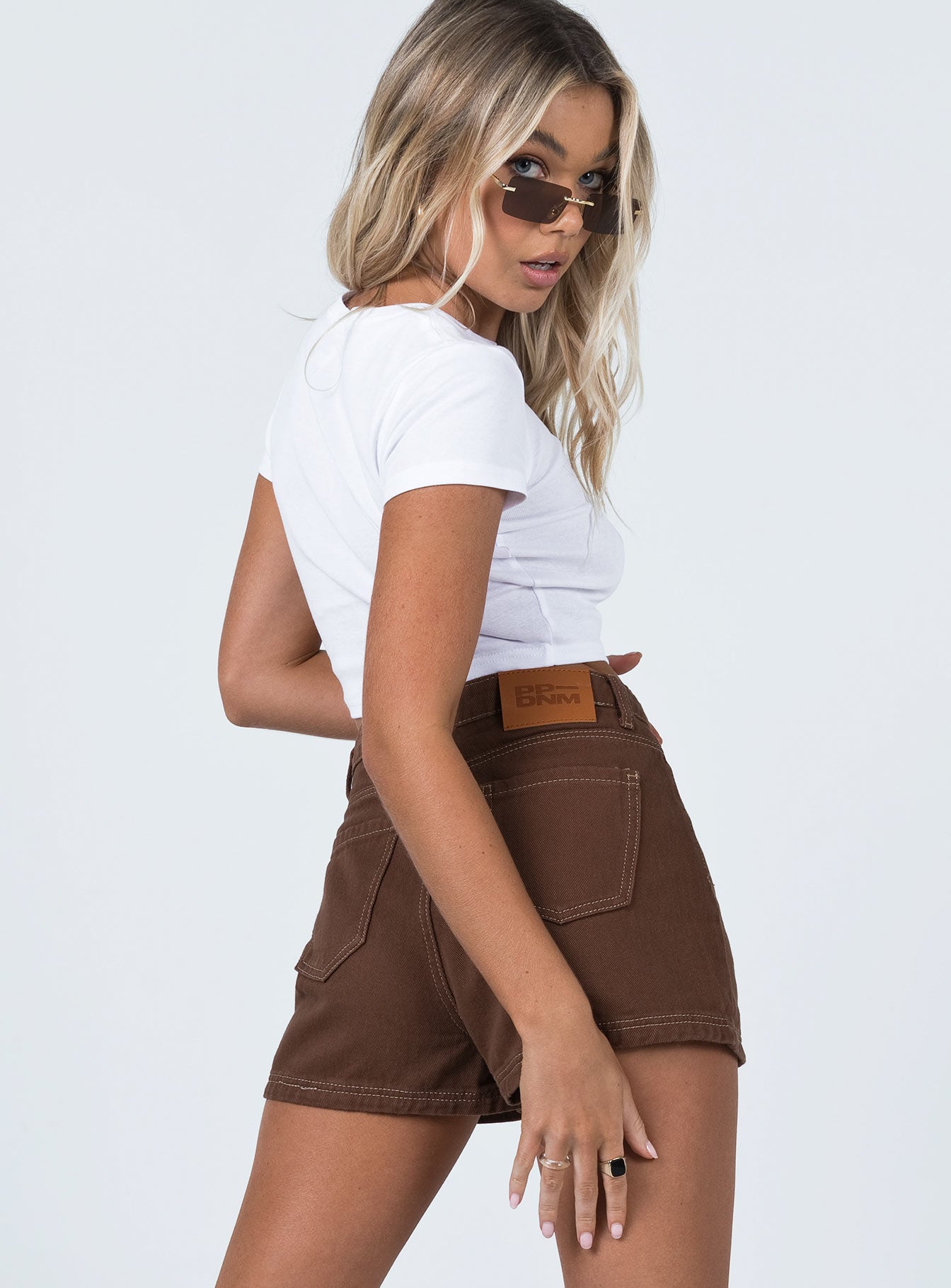 side view of model wearing Princess Polly Darby A Line Short Brown High Waisted Shorts 