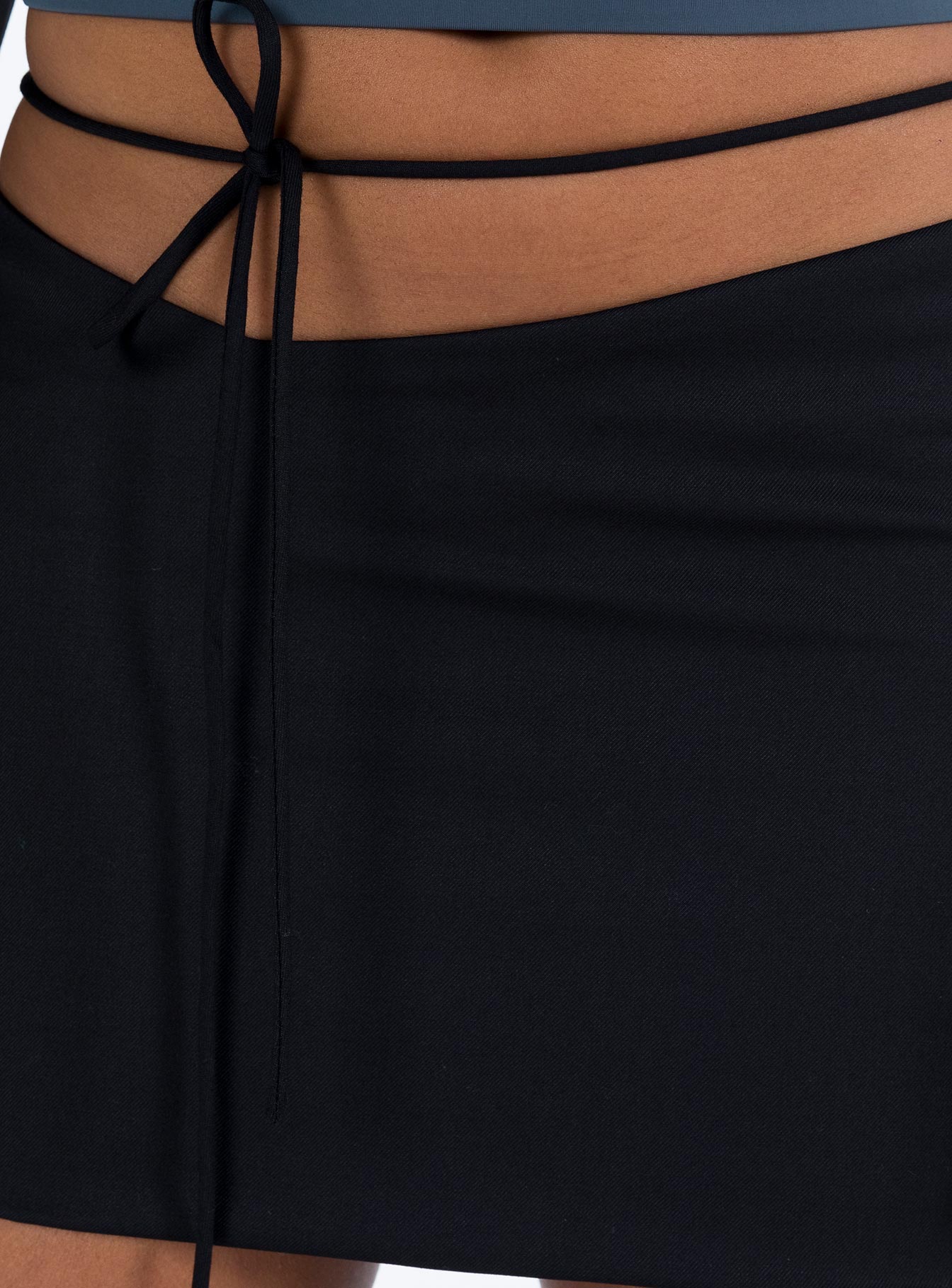 Black mini skirt Low rise Asymmetric waist Tie fastening at waist Invisible zip fastening at side